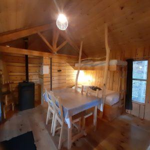 Cabane en bois chaleureuse avec table à manger et lit en mezzanine.