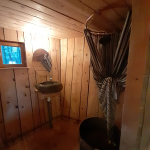 Cabane en bois avec douche originale et ambiance chaleureuse en Auvergne-Rhône-Alpes.