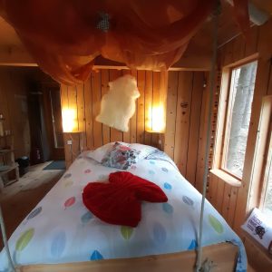Chalet suspendu en bois avec lit douillet et décoration chaleureuse.