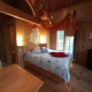 Chalet en bois chaleureux avec lit douillet et décoration colorée, Auvergne-Rhône-Alpes.