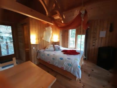 Chalet en bois chaleureux avec lit douillet et décoration colorée, Auvergne-Rhône-Alpes.