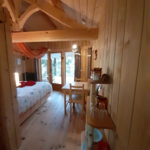 Chalet en bois chaleureux avec lit douillet et coin repas lumineux.