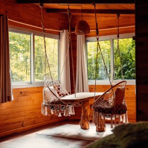 Hébergement insolite en bois avec table suspendue et chaises en macramé.