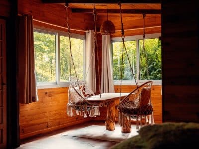 Hébergement insolite en bois avec table suspendue et chaises en macramé.