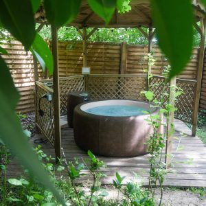 Hébergement insolite en Hauts-de-France avec un jacuzzi entouré de verdure.