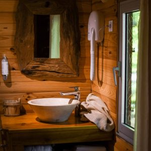 Cabane en bois dans les Hauts-de-France, avec lavabo en pierre et décor chaleureux.