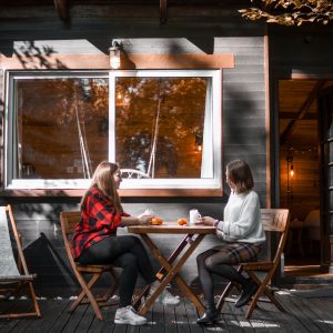 Cabane en bois dans les Hauts-de-France, avec deux personnes prenant le thé en extérieur.