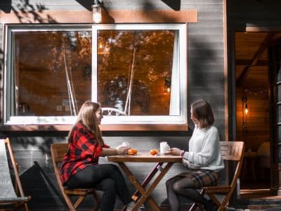 Cabane en bois dans les Hauts-de-France, avec deux personnes prenant le thé en extérieur.