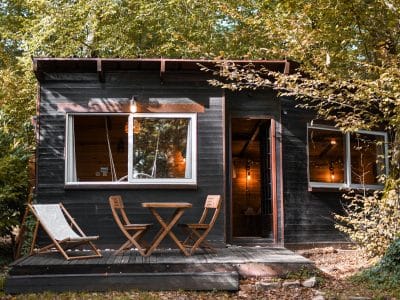 Cabane en bois dans les Hauts-de-France, entourée darbres, avec terrasse accueillante.