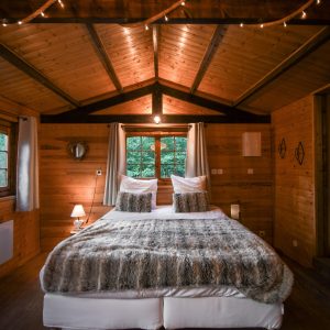 Chalet en bois chaleureux avec lit douillet et lumières tamisées.