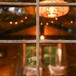 Cabane en bois avec un lustre en rotin illuminant lintérieur chaleureux.