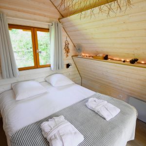 Chalet en bois chaleureux avec lit double et décoration naturelle.