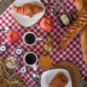 Petit-déjeuner convivial dans un hébergement insolite en Hauts-de-France, sur nappe à carreaux.
