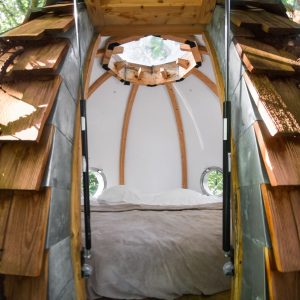 Hébergement insolite en forme de cabane, intérieur en bois avec vue sur la nature.