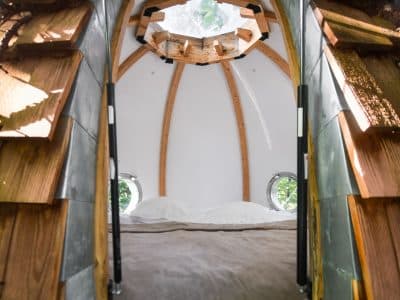 Hébergement insolite en forme de cabane, intérieur en bois avec vue sur la nature.