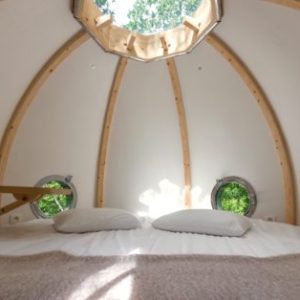 Hébergement insolite en forme de bulle, avec vue sur la nature par un puits de lumière.