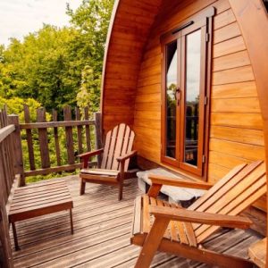 Cabane en bois avec terrasse, chaises confortables et vue sur la nature.