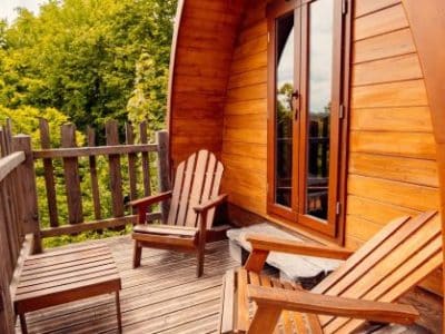 Cabane en bois avec terrasse, chaises confortables et vue sur la nature.
