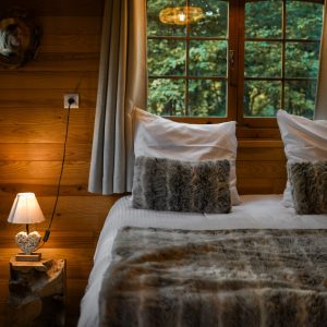 Chalet en bois chaleureux avec lit douillet et lumière tamisée.