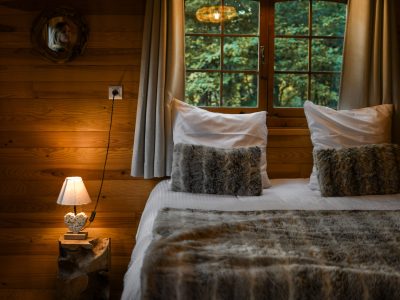Chalet en bois chaleureux avec lit douillet et lumière tamisée.