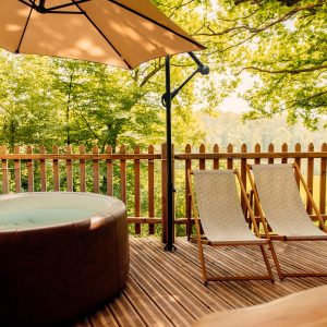 Hébergement insolite en Hauts-de-France avec jacuzzi et chaises longues sous un parasol.
