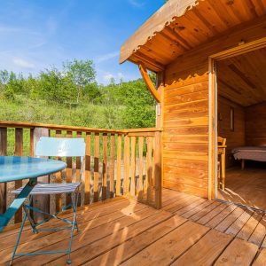 Cabane en bois avec terrasse, vue sur la nature verdoyante en Auvergne-Rhône-Alpes.