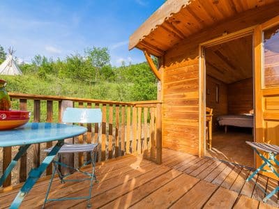 Cabane en bois avec terrasse, vue sur la nature verdoyante en Auvergne-Rhône-Alpes.