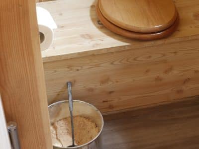 Toilettes sèches en bois dans un hébergement insolite, ambiance naturelle et chaleureuse.