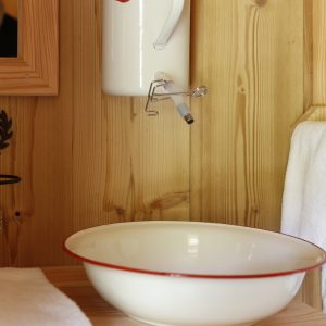 Hébergement insolite en bois avec lavabo vintage en émail et décor chaleureux.