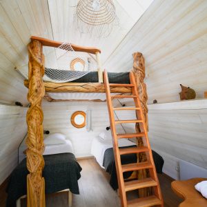 Cabane en bois avec mezzanine, éclairage naturel et décoration chaleureuse.
