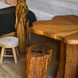 Hébergement insolite en bois, avec mobilier sculpté et table en forme de feuille.