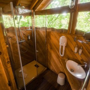 Douche en bois dans une cabane perchée, ambiance nature et confort.