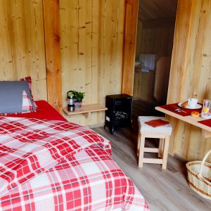 Chalet en bois chaleureux avec lit à baldaquin et petit-déjeuner sur table.