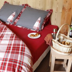 Chalet cosy en bois avec lit à baldaquin et petit-déjeuner gourmand sur table.