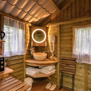 Cabane en bois cosy avec salle de bain, lumière douce et décoration chaleureuse.