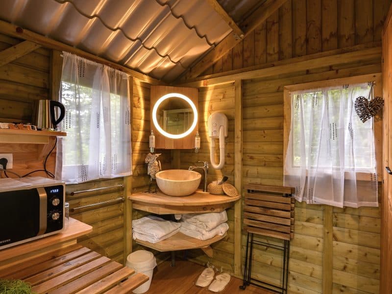 Cabane en bois cosy avec lavabo en pierre et lumière douce. Parfait pour un séjour relaxant.