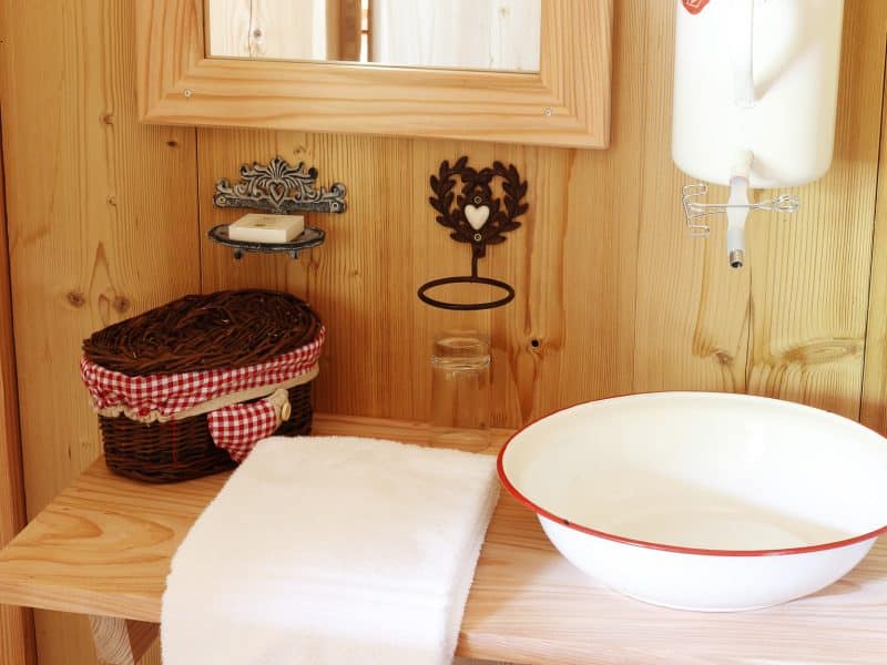 Salle de bain en bois dun chalet, avec lavabo vintage et serviettes blanches.