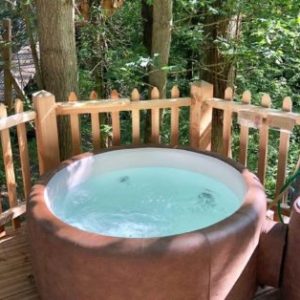 Hébergement insolite en Hauts-de-France avec jacuzzi en bois, entouré de verdure.