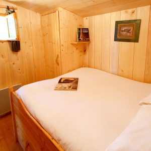 Cabane en bois cosy en Aquitaine, avec un lit douillet et des murs en pin.