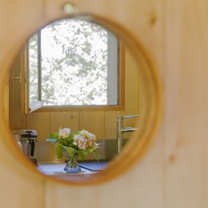 Hébergement insolite en Aquitaine : intérieur en bois avec vue sur un vase de fleurs.