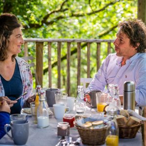 Petit-déjeuner en famille dans une cabane perchée, entourée de verdure en Aquitaine.