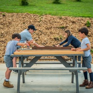 Hébergement insolite en Aquitaine : enfants jouant autour dune table en bois en pleine nature.