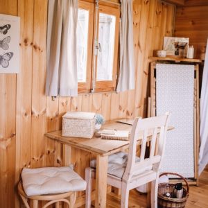Intérieur dun chalet en bois, avec une table et des chaises blanches, ambiance cosy.