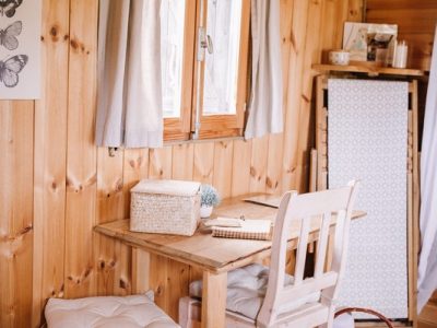 Intérieur dun chalet en bois, avec une table et des chaises blanches, ambiance cosy.