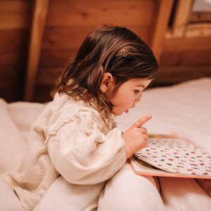 Enfant lisant dans un chalet en bois, hébergement insolite en Pays de la Loire.