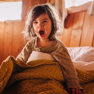 Enfant se réveillant dans un hébergement insolite en bois, ambiance chaleureuse.