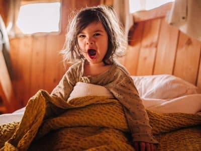 Enfant se réveillant dans un hébergement insolite en bois, ambiance chaleureuse.