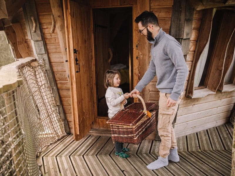 Cabane dans les arbres, bois naturel et accueillant, moment convivial en famille.