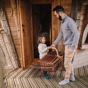 Cabane perchée dans les arbres, avec un homme et une enfant portant un panier.