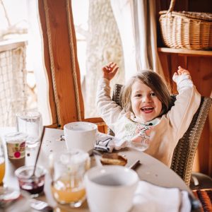 Cabane perchée en Pays de la Loire, enfant joyeux à table avec vue sur la nature.